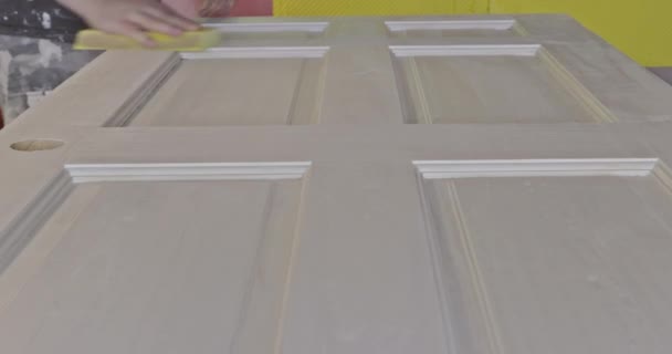 Carpenter in work on worker sanding wooden interior door after primer with sanding block — Stock Video