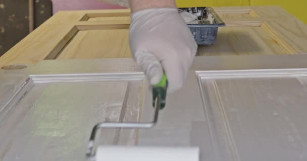 Restauración de manos de pintor con guantes pintando la puerta usando rodillo de mano — Vídeos de Stock