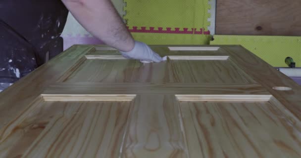Χέρι του επισκευαστή ζωγραφική με γάντια σε ένα πινέλο εφαρμογή βερνίκι χρώμα πόρτες ξύλου χύτευση τελειώματα με πινέλο — Αρχείο Βίντεο