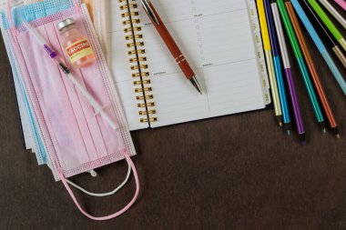 Okul saatleri çeşitli okul malzemelerinin malzeme malzemelerinin üzerinde tıbbi maskeler ile covid-19 coronavirus