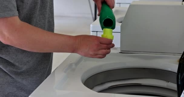 Een vrouw giet zeep poeder, giet conditioner, verzachtend in van de wasmachine — Stockvideo