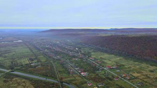 Bovenste antenne-venster uitzicht op grote hoogte bovengronds uitzicht op het platteland van Karpaty over de buitenwijk dorp in de buurt van de berg — Stockvideo