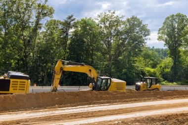 Yeni bir asfalt yolun yapımında. Kazıcılar, yeni yol inşaatında çalışan mezunlar.
