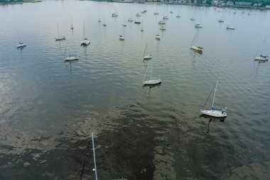 Güneşli bir havada direklerle yüzen bir çok yatın havadan görüntüsü.