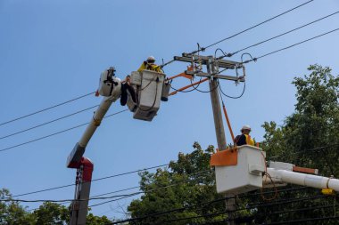 Kasırgadan sonra elektrik hatlarında çalışan adamlar hasarı gidermek için destek sağlıyorlar.