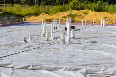 İnşaat alanında beton dökülmesi için temel plaka hazırlayan yeni bir evde PVC drenaj boruları.