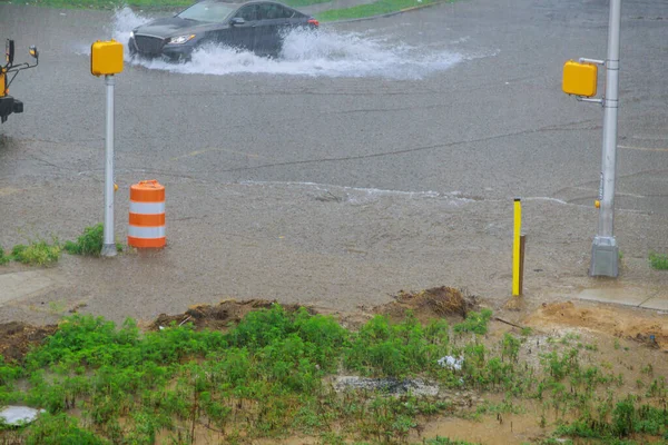 大規模なスプラッシュ水の中に道路を洪水大規模な水たまりを介して速く行く車 — ストック写真