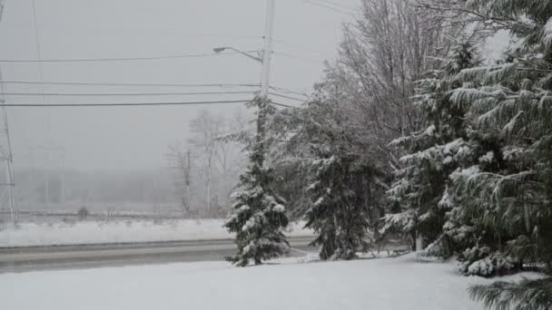 Sníh se zasněženou silnicí v malém městečku v zimě — Stock video