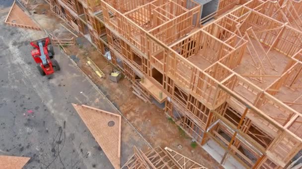 Wood building frame on new residential of under construction a boom truck forklift work — Stock Video