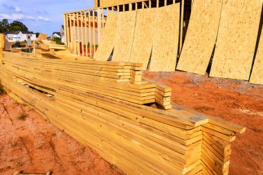 Duvarların çerçevelendiği inşaat sahasında istiflenmiş ahşap kontrplak döşemeler, yeni evlerde çerçeve çalışması.