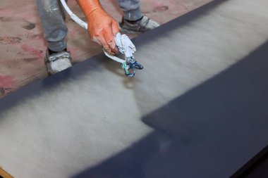 İşçi boya gününde tahta kapı yüzeyine boya sürmek için sprey tabanca kullanıyor..