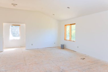 Çıplak duvarlı parlak oda, büyük pencereler, atık kutusu, devam eden yenilemeler..