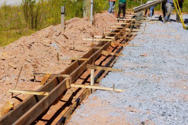 İşçiler inşaata hazırlanan çakıllar boyunca beton kaplama temeller için ahşap formlar oluşturdular.