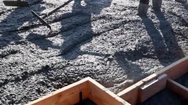 İnşaat işçileri paraşütten ahşap inşaat alanına ıslak çimento dökülüyor beton temeller için yapısal destek sağlayan inşaat demiri şebekesine çimento dökülüyor.