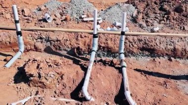 İşçiler iş günü yeni kazılmış şantiyeye atık su tesisatı döşüyorlar.