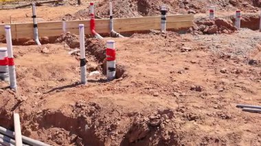 İşçiler iş günü yeni kazılmış şantiyeye atık su tesisatı döşüyorlar.