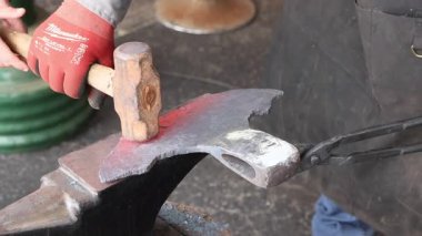 Demirci, balta yapımı sırasında çekiçle parlayan bir metal parçasını ustalıkla şekillendirir.