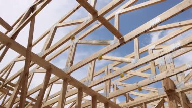 Kalifiye işçiler yeni ev iskeleti inşa ederken ahşap kirişler üzerinde denge kuruyorlar