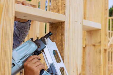 Marangoz inşaat sahasındaki tahta kirişleri hava çivi tabancasıyla tutturuyor.