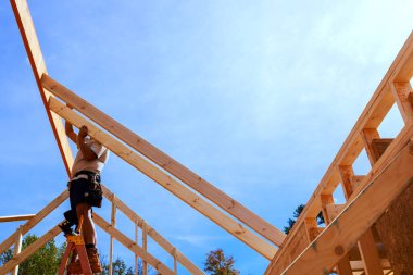 Merdivendeki işçiler çatı kirişlerini yeni ev montajına kuruyor