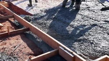İnşaat işçileri temel oluşturmak için taze beton döküyorlar, yüzey çimento tabakasını düzleştiriyorlar