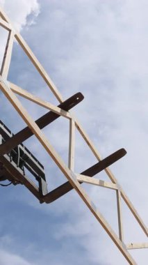 İnşaat işçileri, çerçeve montajı altındaki inşaat sahasında büyük ahşap kirişler açmak için tele-denetleyici vinç kullanıyor.