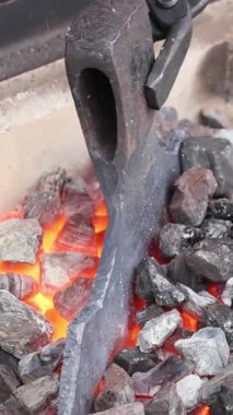 Usta demirci, balta yaparken sıcak metali manipüle etmek için maşa kullanır.