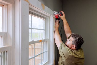 İnşaatçı odadaki pencerenin etrafına bukle uyguluyor. Kesinlik çalışması için elektrikli araç kullanıyorlar.