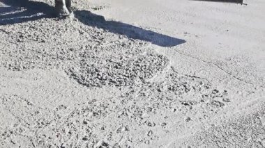 İşçiler, güneşli şantiyedeki ahşap çerçeveye beton dökerek temel üzerine yoğunlaşırlar..