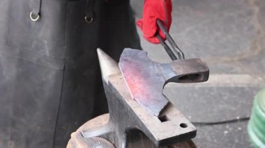 Eldivenler, örsün üzerinde çekiç kullanarak parlayan baltaları şekillendirirken zanaatkarın elini korur.