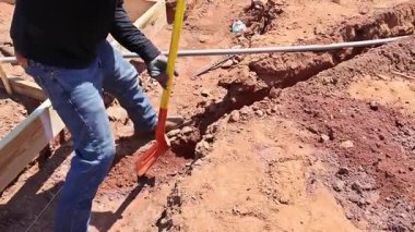 İnşaat işçisi inşaat alanındaki toprağı kazmak için kazı aracı kullanıyor.