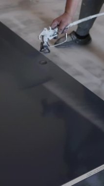 Boyacı, kapalı alanda büyük ahşap tahta boyamak için sprey tabanca kullanıyor..