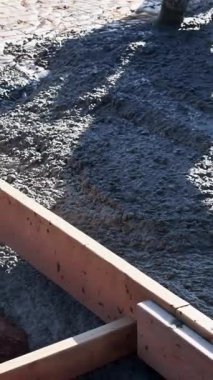 İnşaat işçileri temel oluşturmak için taze beton döküyorlar, yüzey çimento tabakasını düzleştiriyorlar