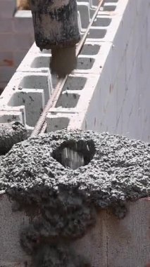 İnşaat işçisi blokları betonla doldururken, temelleri beton pompasıyla inşa ediyor