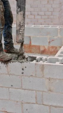 İnşaat işçisi açık havada inşaat yaparken ustalıkla betonu bloklara dolduruyor..