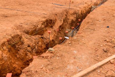 İşçiler, doğru temel yerleştirme için işaretlenmiş kuru arazide hendek kazarak inşaata hazırlanıyorlar..