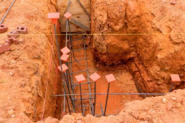 İşçiler kenar mahallelerdeki yeni bina temeli için çelik inşaat demiri kuruyorlar..