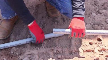 10 Ekim 2025 New York ABD 'li işçiler PVC boruları monte ediyor, güvenlik teçhizatı, eldiven ve sağlam botlar giyiyorlar..