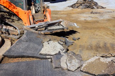 İşçiler yol onarımı için hazırlanırken, inşaat alanındaki eski kaldırımları ağır makineler yıkıyor