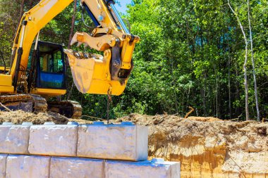Ağır makineler inşaat alanındaki büyük blokları kaldırarak istinat duvarı oluşturmaya çalışıyor
