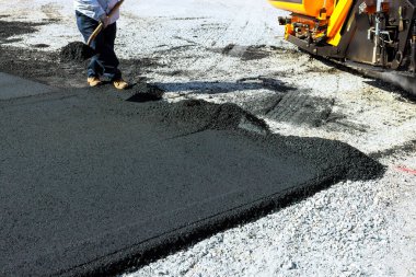 İnşaat işçisi asfalt döşeyip kaldırım makinelerini çalıştırıyor.