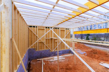 İşçiler, temel destek kirişlerini gösteren ahşap çerçeveli yeni bir bina inşa ediyorlar.