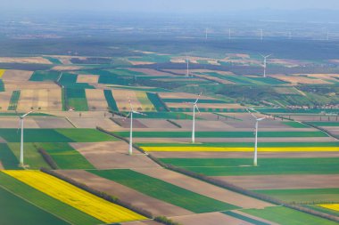 Rüzgar türbinleri yeşil sarı alanlar boyunca dimdik durarak Avusturya, Viyana 'da yenilenebilir enerji yakalıyorlar.