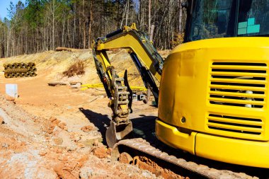 Kazıcı, ormanlık alanın yakınındaki hendek inşaatında yer kazıyor.