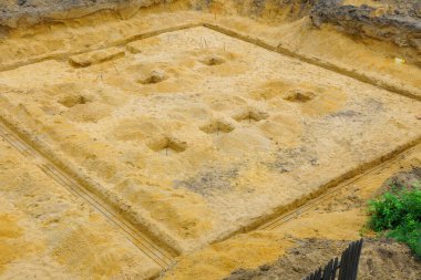 Kazı çalışmaları, destek yapıları için zeminde birkaç delik açılmış olan inşaat sahasında görülebilir..