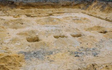 İşçiler, gelecekte kırsal alandaki inşaat faaliyetleri için kumda birkaç çukur kazılmış inşaat sahası hazırlıyorlar..