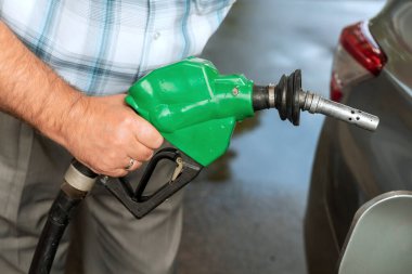 Bireyler benzin istasyonundaki araca benzin koymak için yeşil yakıt başlığı kullanıyor.