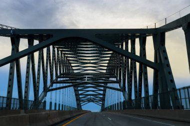 Büyük metal köprü, gecenin erken saatlerinde yolun iki tarafını bulutlu gökyüzüne bağlar..