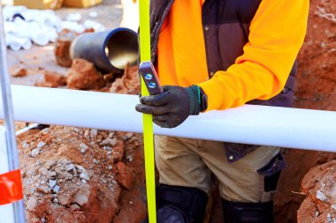 İşçi inşaat alanındaki borunun konumunu kontrol etmek için seviye aracı kullanıyor