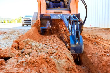 İşçi inşaat sahasında çukur açmak için siper kazıyor..